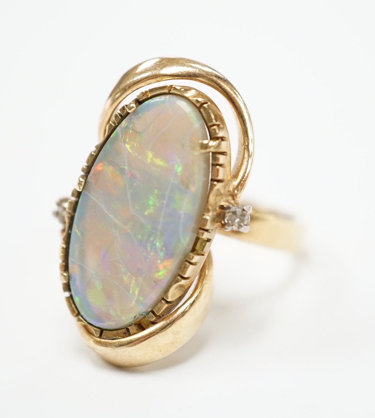 A yellow metal and oval cut black opal set dress ring, with two stone diamond chip set border, size M, gross weight 8.2 grams.